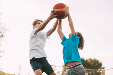 Two teenage boys play basketball on the Playground. Athletes fight for the ball in the game. Healthy lifestyle, sports