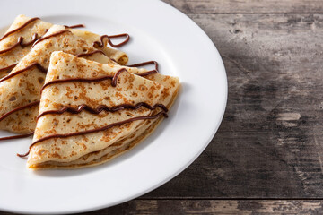 Sweet crepes with chocolate on wooden table. Copy space	