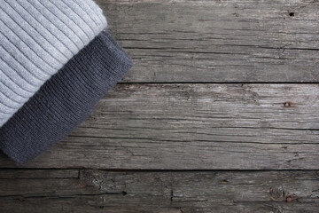 Stack of folded grey scarfs on grunge old wooden boards. Copy space, top view. Autumn background,...