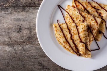 Sweet crepes with chocolate on wooden table. Copy space	