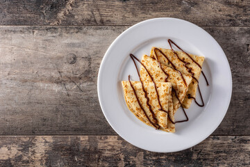 Sweet crepes with chocolate on wooden table. Copy space	