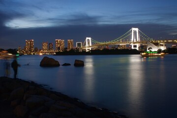 お台場夜景　レインボーブリッジ　ライトアップ白
岩場と釣り人のシルエット