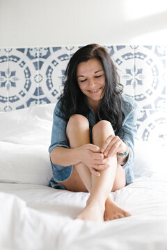 beautiful smiling woman in jeans sweater on her bed
