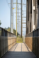 Fussgängerbrücke neben Einenbahnbrücke, Metallgeländer, Holzboden, industrie, blauer Himmel Strommasten