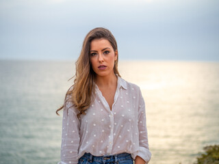 Mujer posando con el mar de fondo durante la puesta de sol