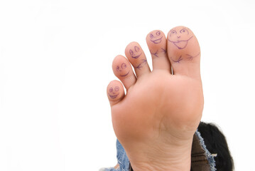 toes on a female leg with painted faces on a white background