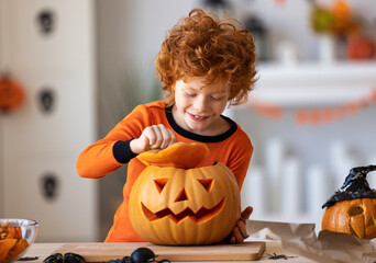 Happy redheaded boy in  costume laughs and with  pumpkin Jack o lantern   during a Halloween celebration.