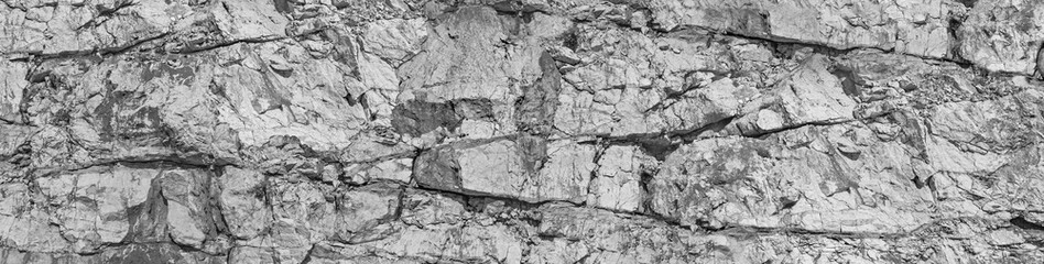 Fototapeta na wymiar Deep damages of high shore, gaps split, cavity, groove track on a big sharp stones. Debris, scratch marks of cut ruined blocks rock. Gray dirt bump map of old grunge steep cliff for 3d volume backdrop