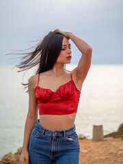 Mujer joven posando con el mar de fondo durante el atardecer