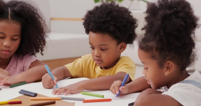 Little boy and girl drawing pictures to paper at home. They learning to draw pictures together.