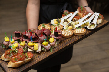On a wooden stand lies a canapé sandwich with tomato olives parmesan cheese