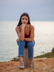 Mujer joven posando con el mar de fondo durante el atardecer