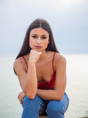 Mujer joven posando con el mar de fondo durante el atardecer