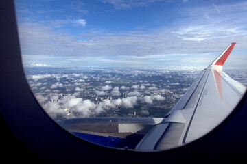 View from the airplane window.
View of the wing of a flying plane and the city under the clouds.