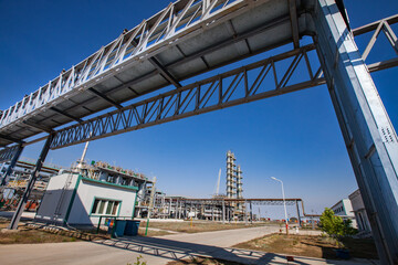 Petrochemical plant in a desert. Wide-angle view on pipelines and oil distillation towers (refining columns) on blue sky background.