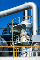 Petrochemical plant. Close-up of oil refinery column (distillation tower) and pipes on blue sky.
