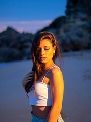 Mujer joven posando en la playa durante el atardecer