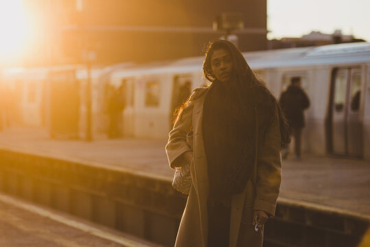 Young woman holding headphones and waiting for subway train