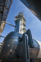 Heat exchanger and pipelines on distillation tower and blue sky background. Oil refinery plant....
