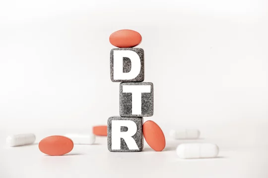 a group of white and red pills and cubes with the word DTR Deep tendon reflexes on them, white background. Concept carehealth, treatment, therapy.