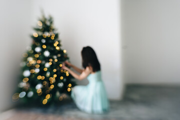 Female, wearing feminine dress, decorating lower branch of Christmas tree, defocused