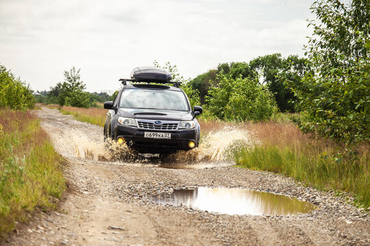 Khabarovsk, Russia - June 26, 2020: Black Subaru Forester driving on a  dirt road with puddles.