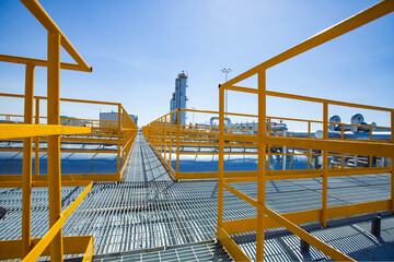 Oil refinery and gas processing plant. Yellow balustrade and distillation towers (refining columns). On blue sky background.