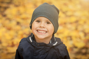 Portrait of a little boy happily smiling in the autumn forest.