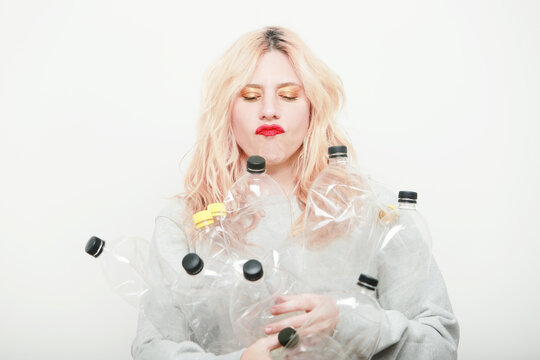 Caucasian woman with many plastic bottles in her arms and expression of disapproval