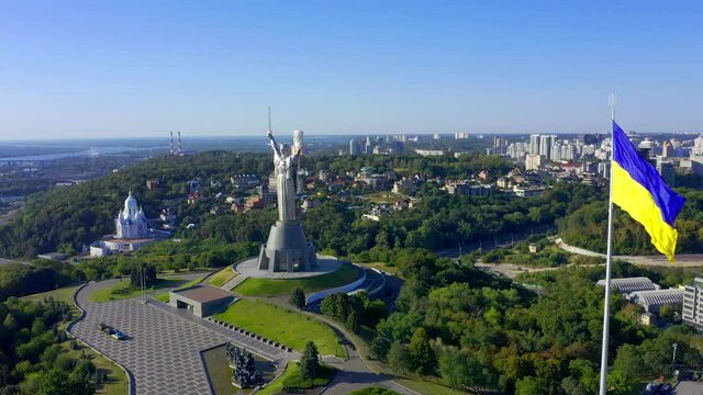 Flying a drone to the famous monument in Ukraine Motherland. Cinematic aerial view to the Motherland statue in the Kiev and national flag. Ukraine.  Monument of the Motherland in Kiev.