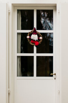 Felt Santa Claus miniature inside wooden garland hangs from door