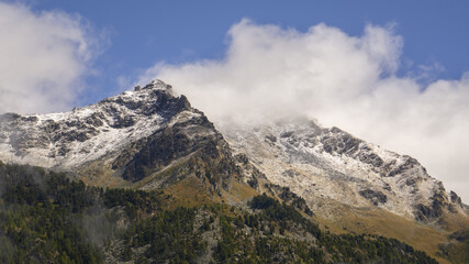 Fototapeta na wymiar Titolo: View of Corno Bussola (Valle d'Ayas, AO) surrounded by clouds and covered by snow after a storm in august.