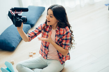 Enthusiastic teenager with modern camera at home
