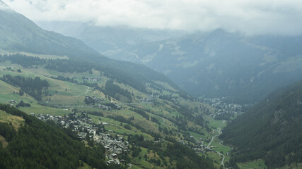 Naklejka premium View from above of the Ayas Valley and Champoluc on a foggy day (Aosta Valley) with Antignod village in close-up 