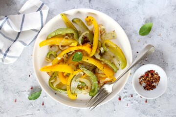 Roasted yellow and green bell pepper salad in white plate. Top view with copy space.