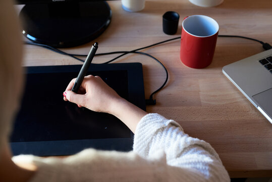 Woman using pen tablet at desk.