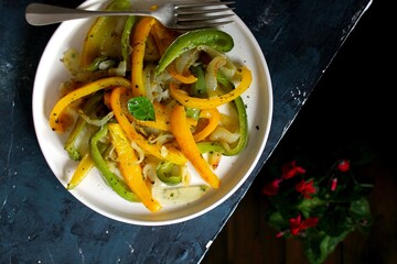 Roasted yellow and green bell pepper salad in white plate. Top view with copy space.