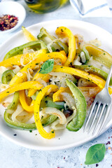 Roasted yellow and green bell pepper salad in white plate. Top view with copy space.