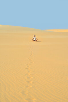 Young girl meditating in golden sands of a desert ander bright b