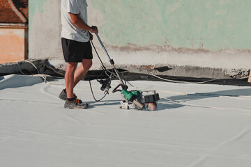 Worker welding pvc roof membrane by heater with welder machine