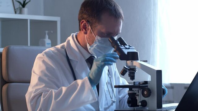 Professional medical doctor working in laboratory using microscope.