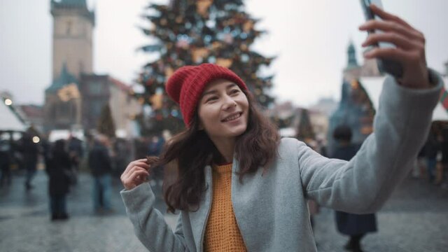 Pretty white woman taking selfie on phone on xmas background. Travel, happiness, xmas, holiday concept. Filmed on RED camera, 10 bit clolor