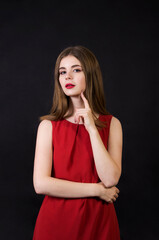 Obraz premium A beautiful girl in a red dress with long hair and a make-up.