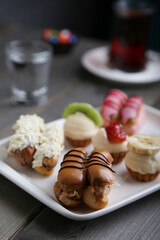 Eclairs and mini tarts on a white plate vertical view