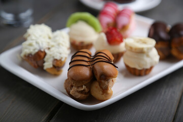 Eclairs and mini tarts on a white plate horizontal view