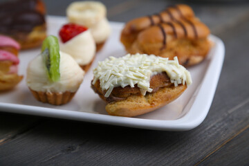 Eclairs and mini tarts on a white plate close up
