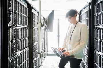 Server room technician standing at work station typing with door