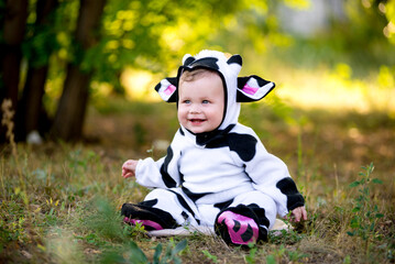 Year of the bull. A child in a fancy dress of a bull on a meadow smiles cute. Kid in Halloween Cow...