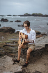 Romantic young man with a guitar on the beach