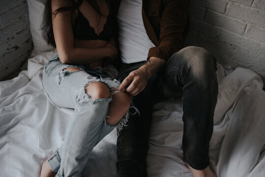 Young fashionable couple in ripped jeans cuddling on floor in living room